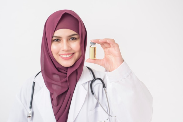 Belle femme médecin avec hijab tient le vaccin sur fond blanc