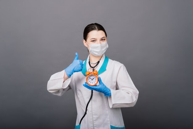 Belle femme médecin en masque de protection en détournant les yeux et en pensant à quelque chose.