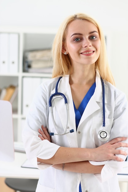 Belle femme médecin souriante debout dans le portrait de bureau