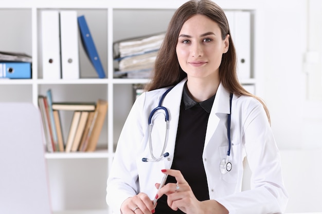 Belle femme médecin souriante avec stylo argenté