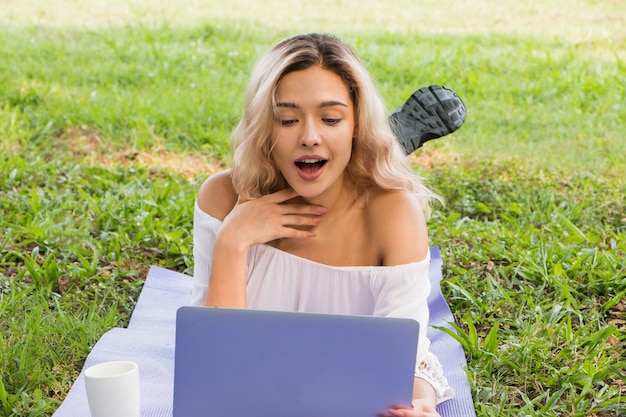 Photo belle femme sur les médias sociaux en ligne avec un ordinateur portable en plein air dans un parc