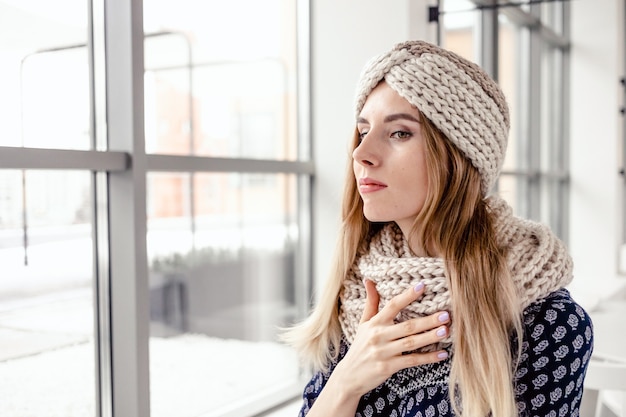 Belle femme mignonne portant bonnet et écharpe d'hiver tricoté sur fond de café.