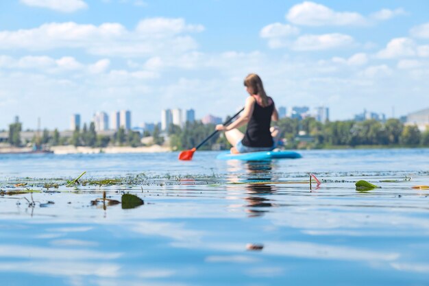 Belle femme millénaire sur une planche de SUP sur la rivière