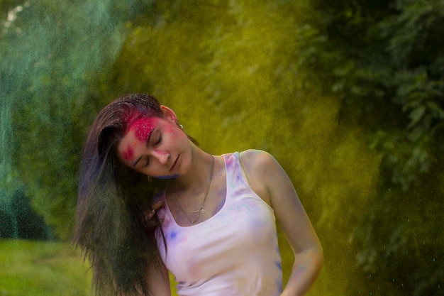 Belle femme avec mouvement de cheveux et poudre de couleur autour d'elle