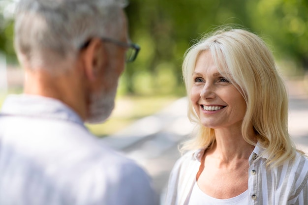 Belle femme mûre regardant son mari avec amour pendant qu'ils se tiennent dehors