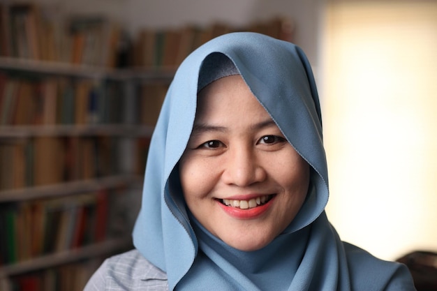 Une belle femme musulmane asiatique heureuse souriant à la caméra étudiante dans la bibliothèque en gros plan