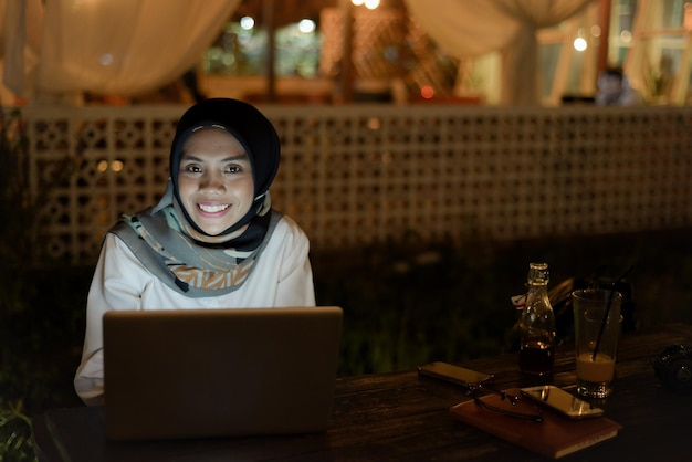 Belle femme musulmane asiatique tenue décontractée travaillant à l'aide d'un ordinateur portable la nuit