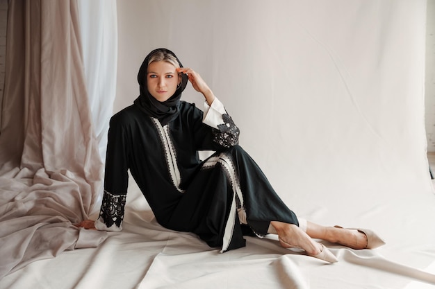 Belle femme musulmane en robe abaya arabe traditionnelle sur fond gris