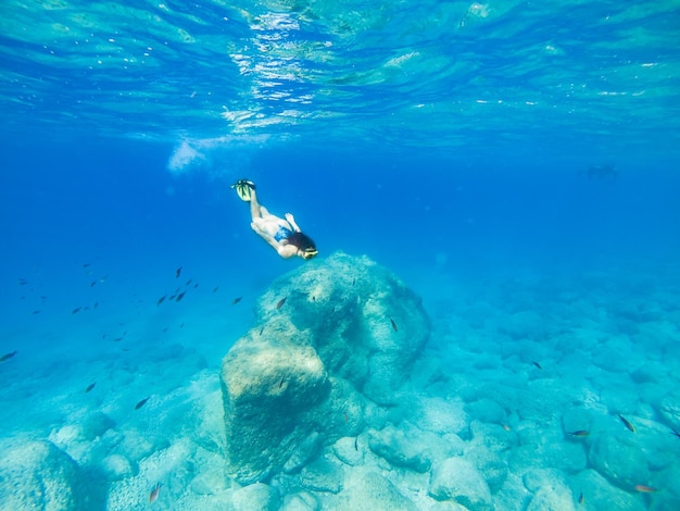 Belle femme nageant sous l'eau avec masque de plongée et palmes