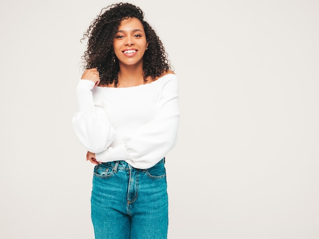 Belle femme noire avec une coiffure de boucles afro. Modèle souriant en pull et vêtements jeans à la mode