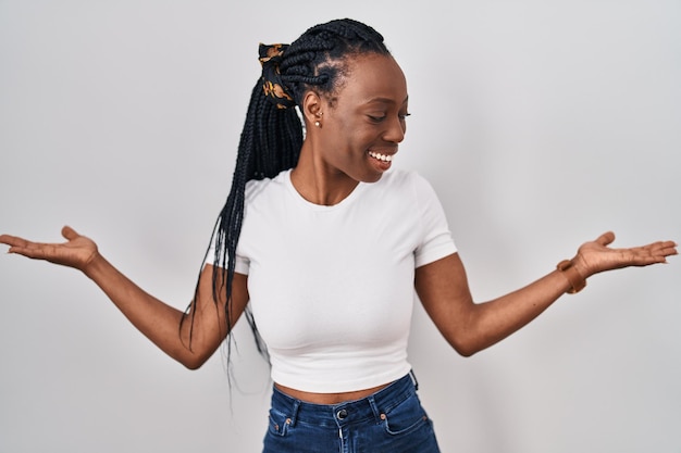 Belle femme noire debout sur fond isolé souriant montrant les deux mains paumes ouvertes, présentant et comparant la publicité et l'équilibre