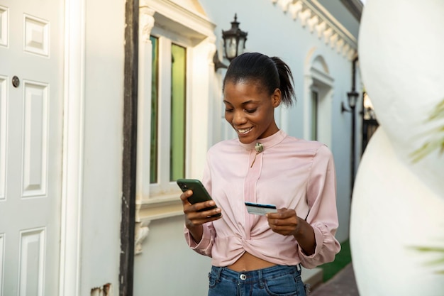 Belle femme noire faisant du shopping en ligne à l'aide d'un téléphone portable