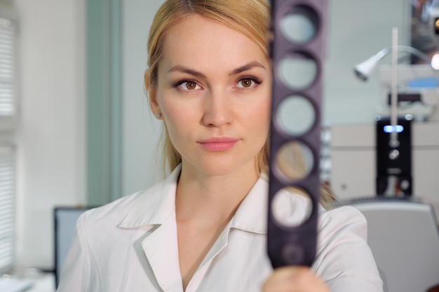 Belle femme ophtalmologiste avec dispositif ophtalmologique dans l'armoire.