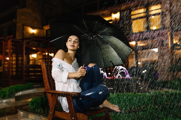 Belle femme avec le parapluie assis sur le banc
