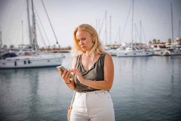 Belle femme parlant au téléphone sur fond de mer bleue et de yachts