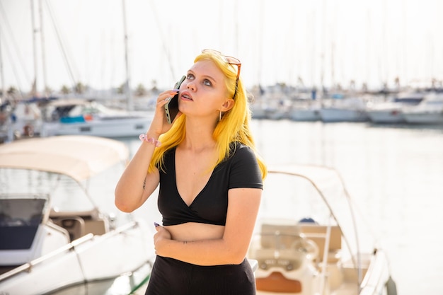 Belle femme parlant au téléphone sur fond de mer bleue et de yachts