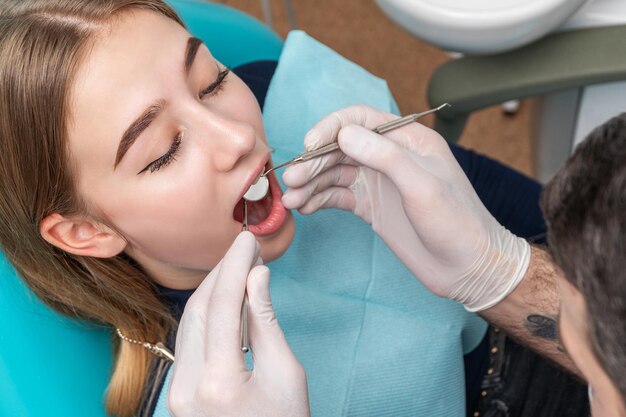 belle femme patiente au rendez-vous chez le dentiste assis sur une chaise avec la bouche ouverte