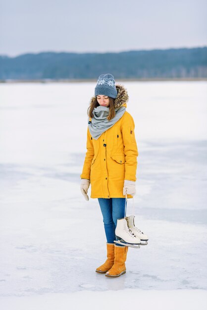 Belle femme avec des patins à glace au milieu d'un lac gelé