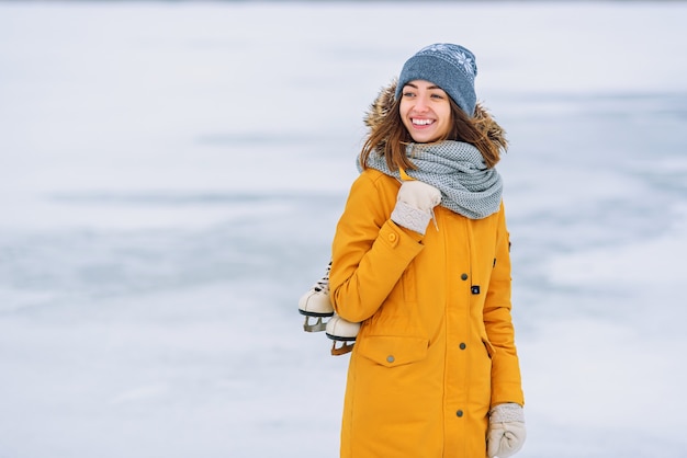 Belle femme avec des patins à glace au milieu d'un lac gelé