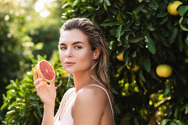 Belle femme à la peau lisse avec un pamplemousse dans les mains