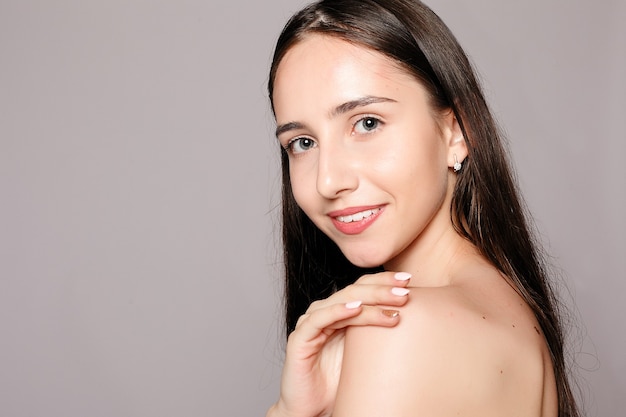 Belle femme avec une peau parfaite et des épaules nues sur fond gris