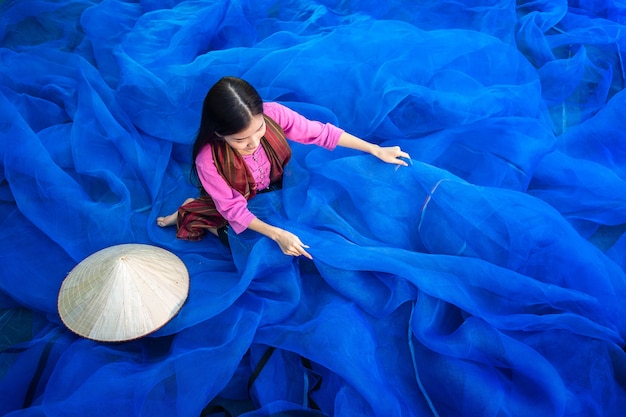 Belle femme pêcheur répare des filets de pêche, pêcheur nettoie la pêche thaïlandaise