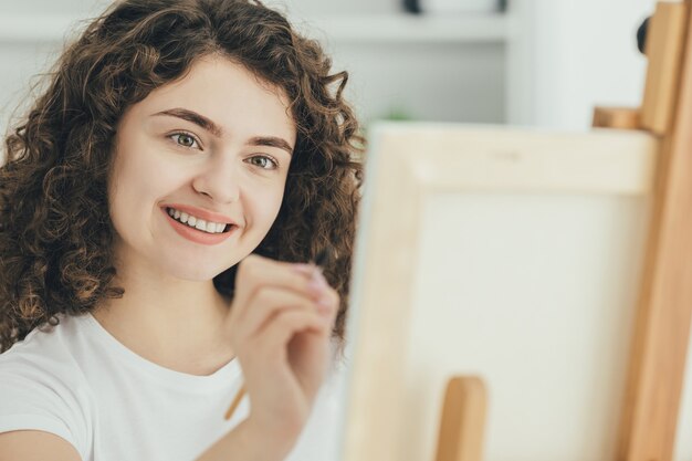 La belle femme peignant une image sur le chevalet