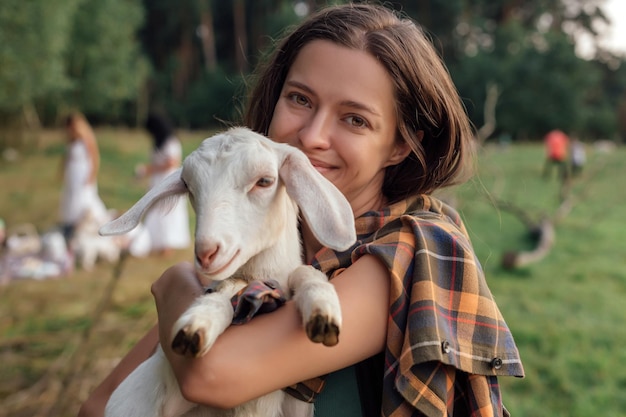 Belle femme avec une petite chèvre à la campagne a de l'amitié dans la nature