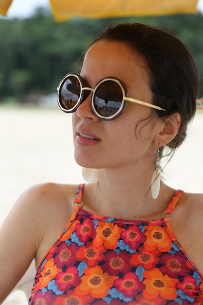 Belle femme sur la plage avec des lunettes de soleil noires avec un beau fond
