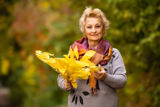 belle femme plus âgée se dresse sur un fond d'automne jaune