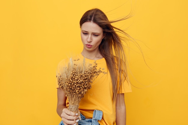 Belle femme portant un chapeau fleurs sèches été style fond jaune