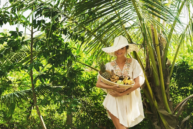 Belle femme portant un chapeau à large bord dans le jardin tropical
