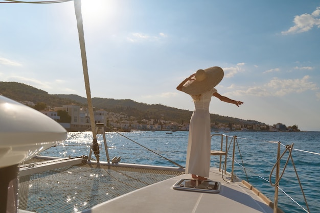 Belle femme portant un chapeau de paille et une robe blanche sur un yacht profite du voyage, Spetses, Grèce, Europe.