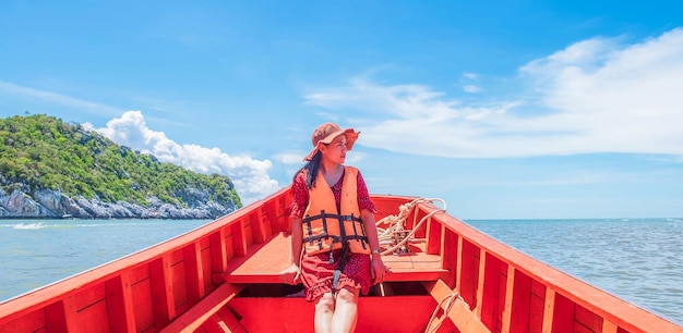 Belle femme portant un gilet de sauvetage est assise à la proue du bateau à l'air détendue, elle voyage seule