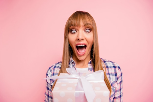 Photo belle femme posant avec boîte-cadeau contre le mur rose