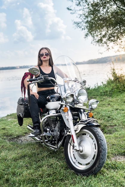 Belle femme posant avec casque et moto