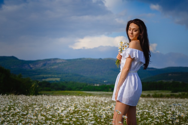 Belle femme posant sur un champ avec des marguerites