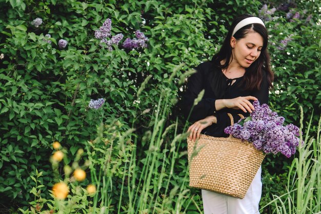 Belle femme posant avec des fleurs lilas l'été arrive