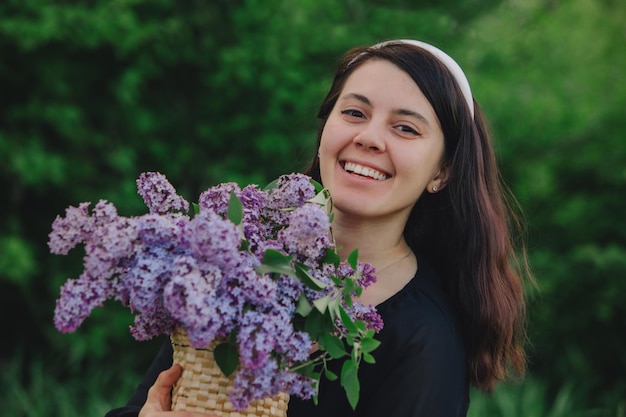 Belle femme posant avec des fleurs lilas l'été arrive