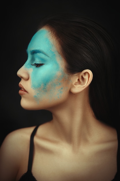 Belle femme posant avec un maquillage bleu créatif