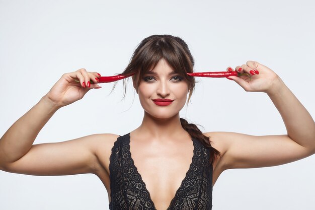 Belle femme posant avec des piments rouges.