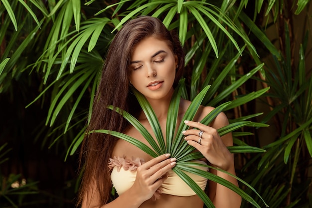 Belle femme posant près de feuilles vertes