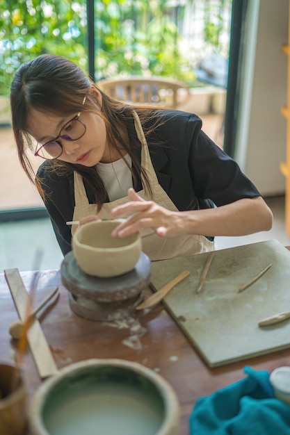 Belle femme potier travaillant sur une roue de potier faisant un pot en céramique à partir d'argile dans un atelier de poterie