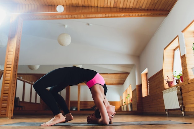 Une belle femme pratique le yoga backbend asana urdhva dhanurasana en faisant face vers le haut en posant un arc au yoga