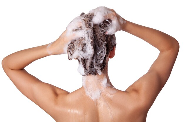 Belle femme prenant une douche et shampouinant ses cheveux. laver les cheveux avec un shampooing. tourné en studio isolé sur fond blanc.