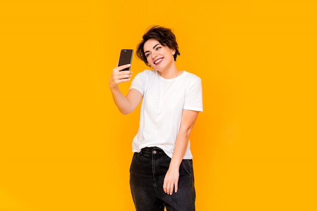 Belle femme prenant selfie à la maison. Jeune fille mignonne parler via un lien vidéo sur un téléphone mobile avec des amis ou des parents. Femme heureuse à l'aide de smartphone pour les amis et les parents d'appel vidéo.