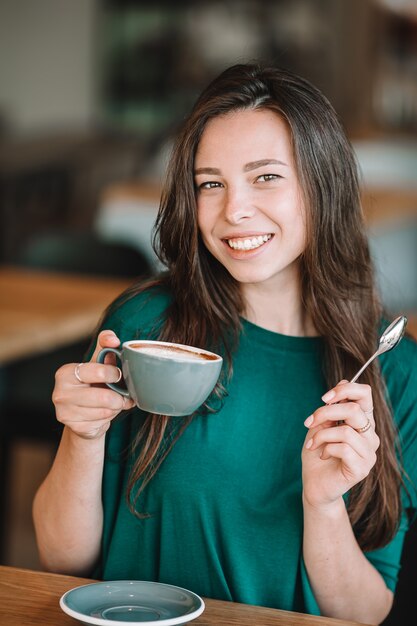 Belle femme prenant son petit déjeuner au café en plein air. Heureuse jeune femme urbaine, boire du café