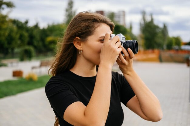 Belle femme prend une photo avec son appareil photo vintage un jour venteux