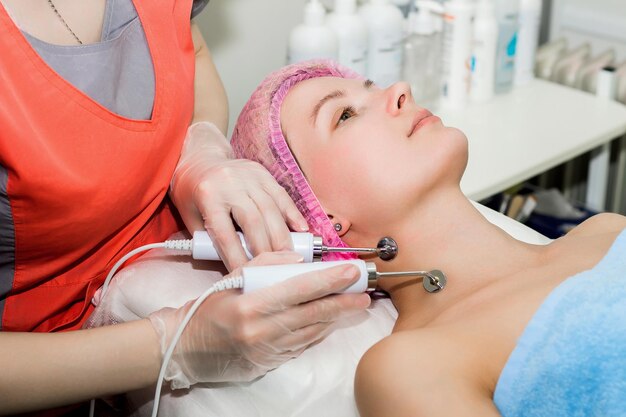 Une belle femme prend une procédure cosmétique pour améliorer l'état de la peau du visage avec des micro-courants