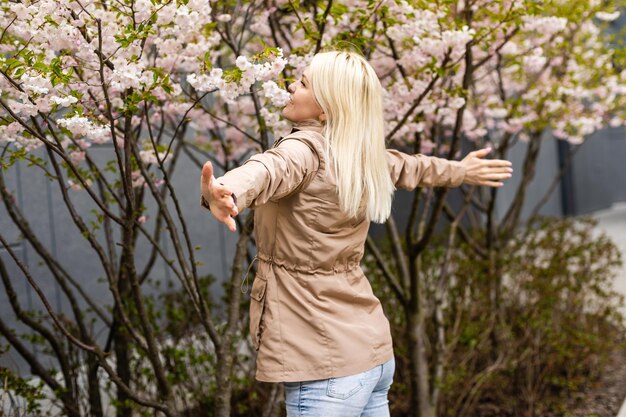 Belle femme profitant d'une journée de printemps ensoleillée dans le parc pendant la saison des fleurs de cerisier.